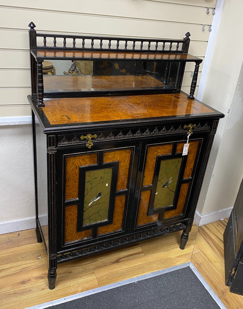A Victorian aesthetic movement ebonised and bird's eye maple two door side cabinet, inset painted panels of birds, width 99cm, depth 44cm, height 141cm